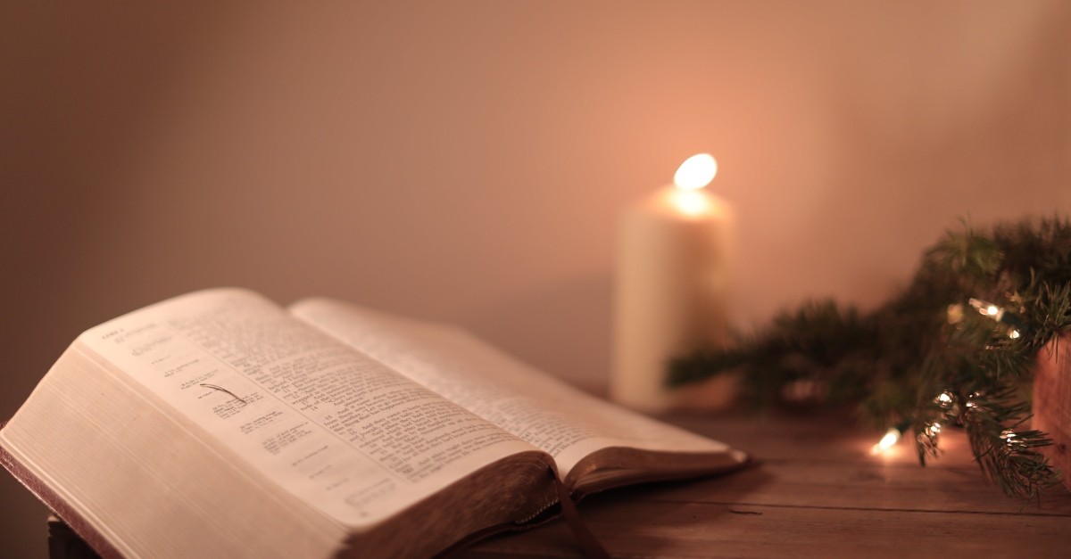 Open Bible next to Christmas candle and wreath