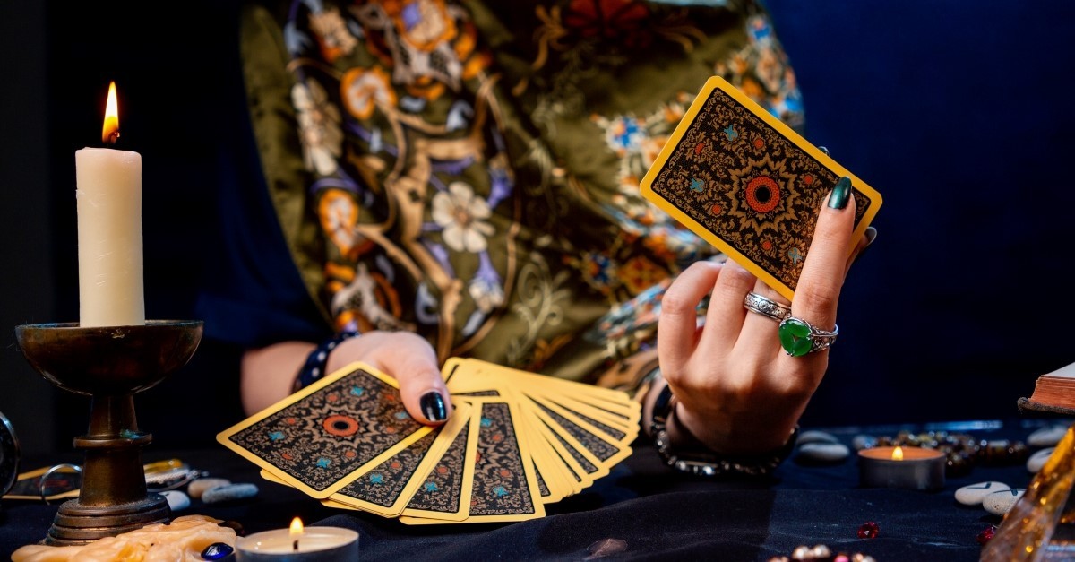 fortune teller holding up cards, where do tarot cards come from are they evil