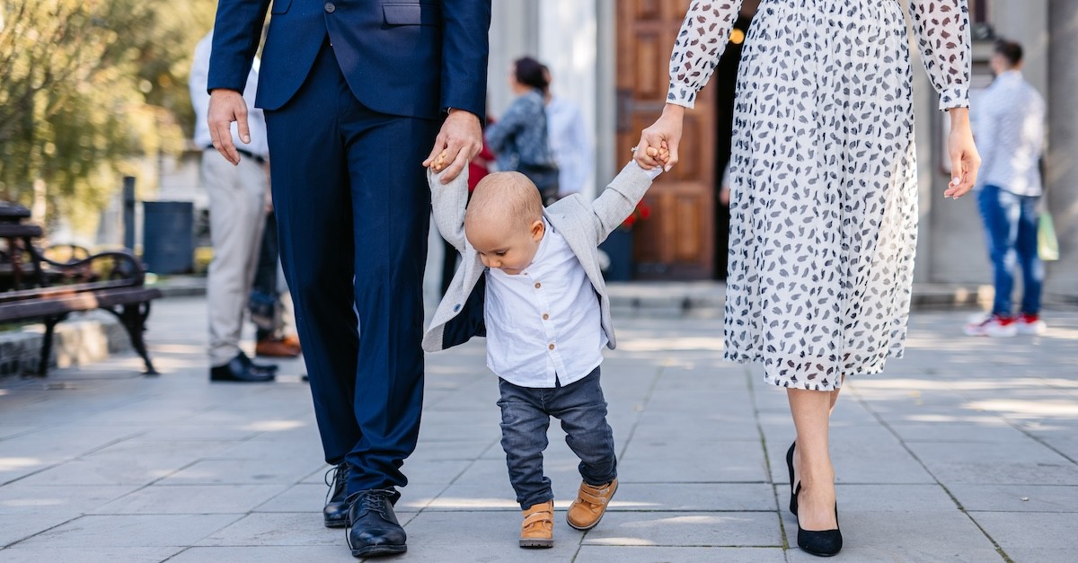 father and mother holding toddler's hands as they walk from church