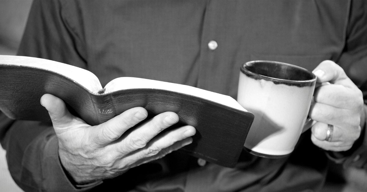 Man holding a cup of coffee and a Bible; why do men hate small groups?