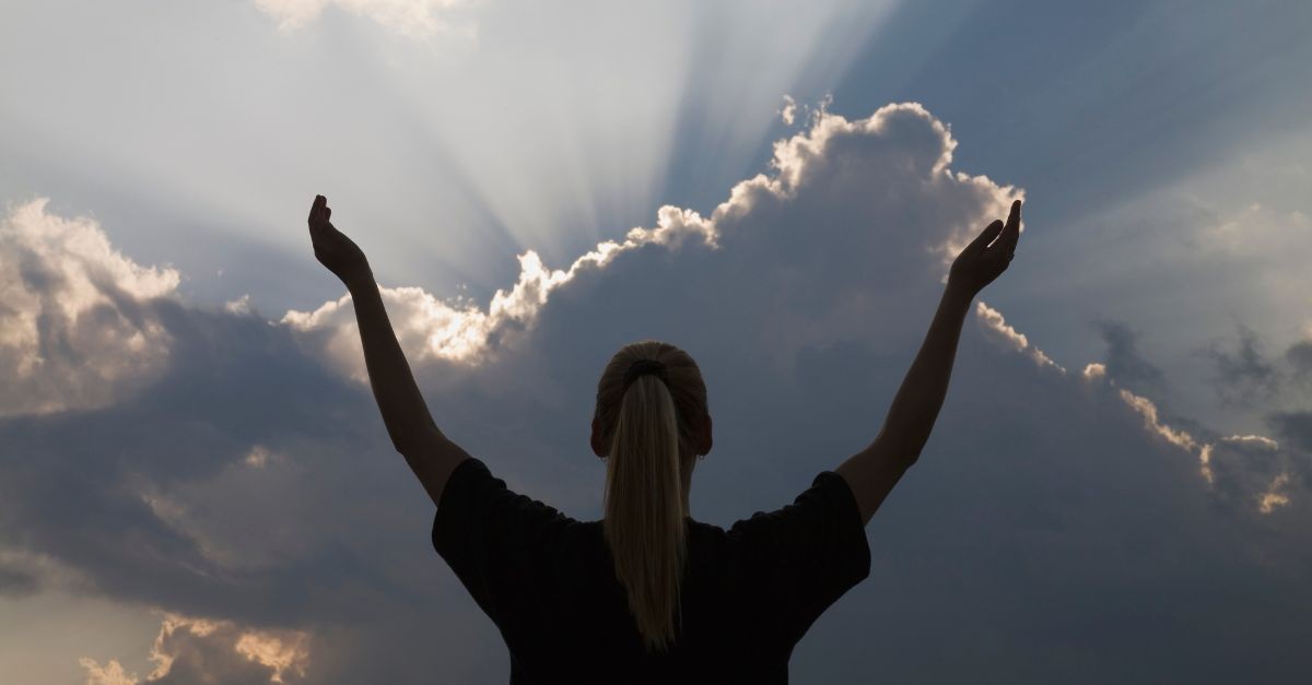 Woman looking up to the clouds, praising God.