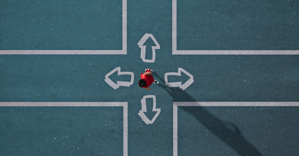 Person standing at a 4-way cross, with arrows pointing in each direction