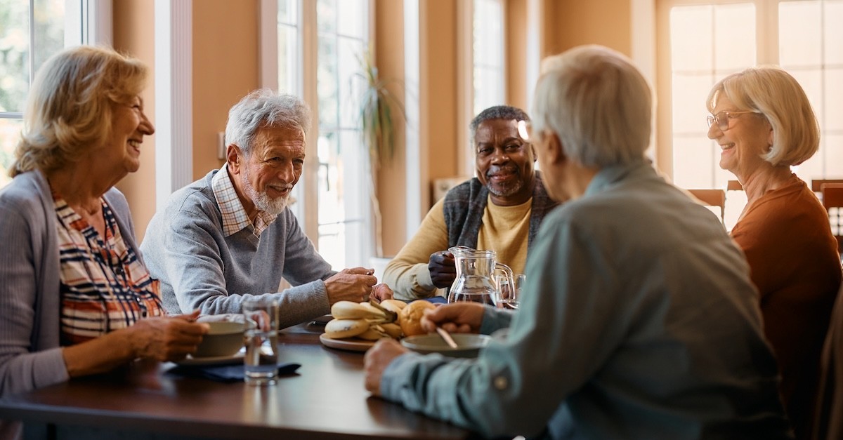 Old senior couple friends talking at table eating