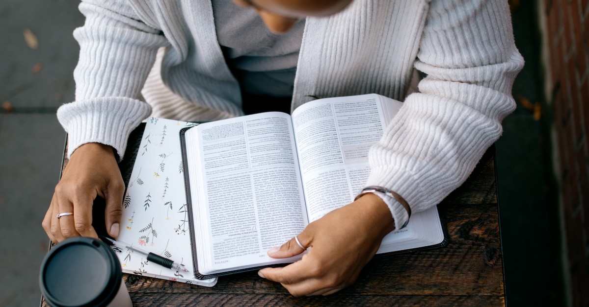 Woman studying reading Bible with notebook