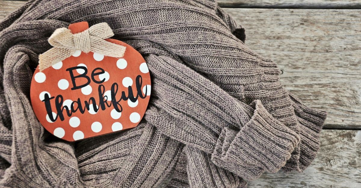 'Be Thankful' sign lying on a sweater; faith is fueled by gratitude