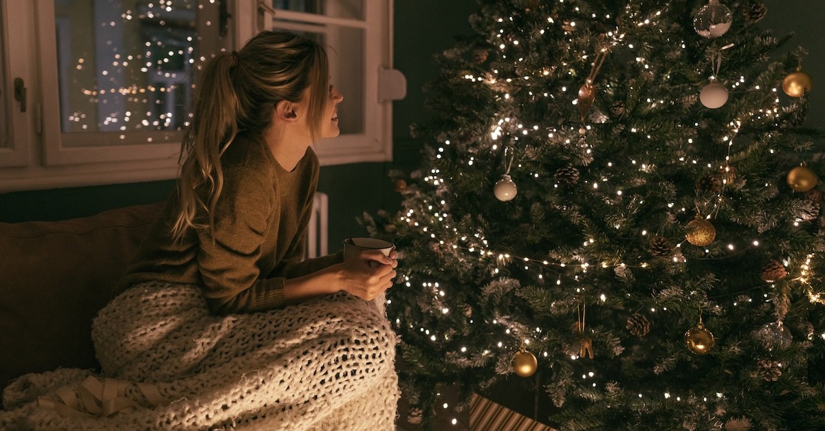 Woman peaceful sitting by Christmas tree with mug