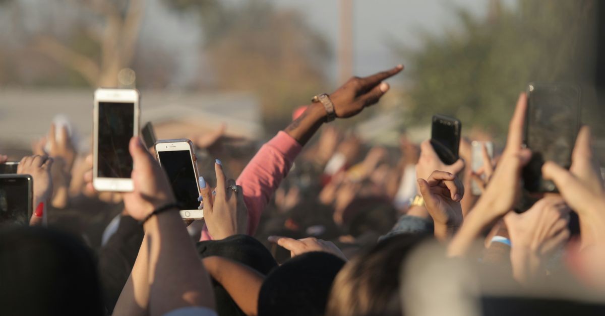 Crown of people holding their phones up: the toll of scrolling.