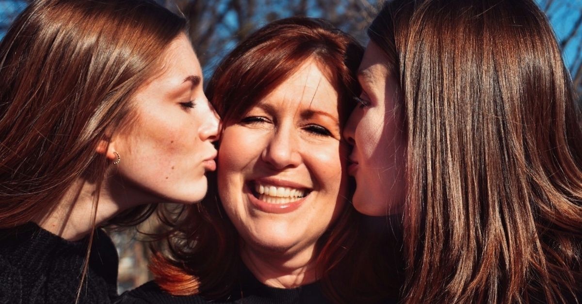 Daughters kissing their mom on the cheeks; encouraging kids of any age.