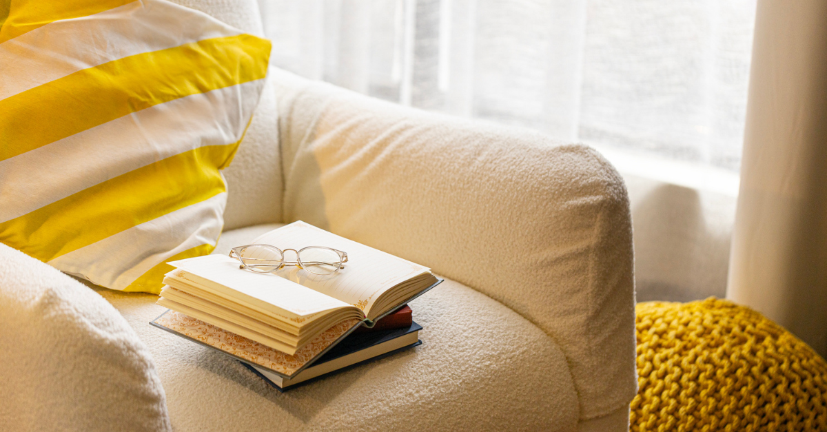An empty armchair by a window with books and glasses, prayers for widow