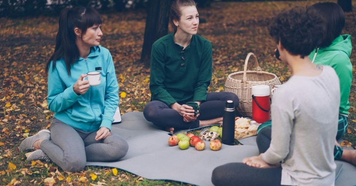 Group of friends sitting outside enjoying a picnic in the fall
