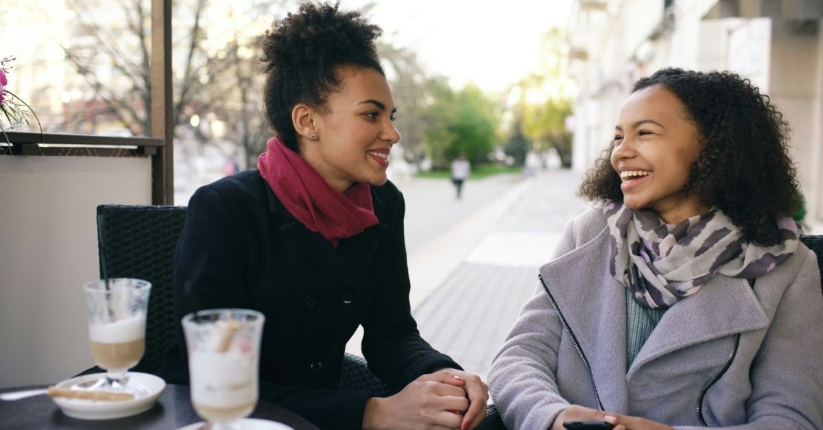 Two friends talking over coffee outside in the fall