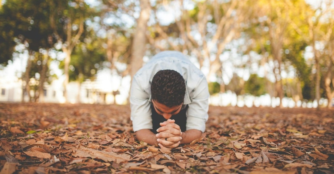 man praying in fall leaves