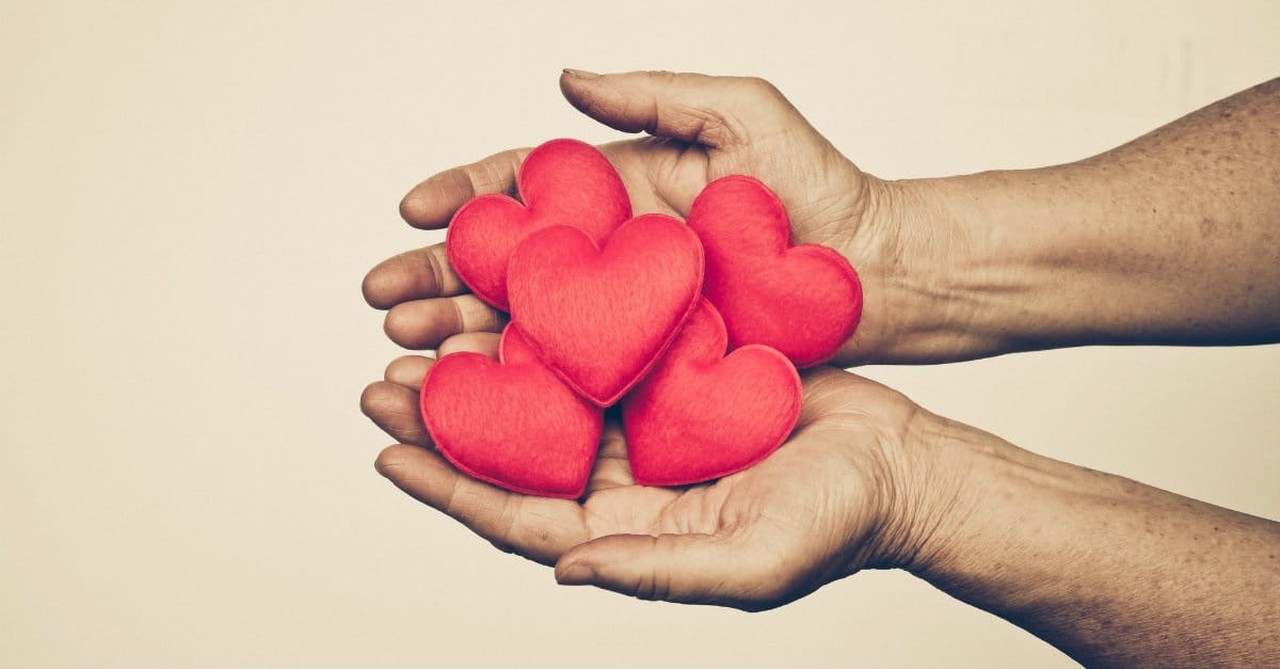 two hands holding 5 red puffy hearts