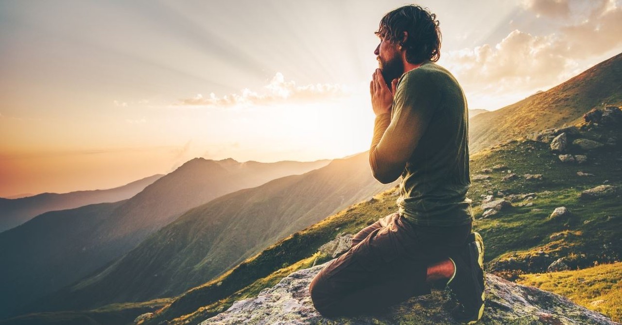 Man kneeling praying on mountain