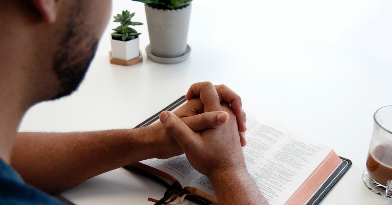 man with hands folded in prayer on open bible, things that god hates