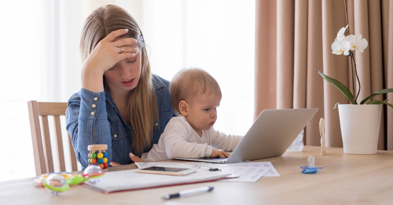 busy mom working from home with baby in her lap