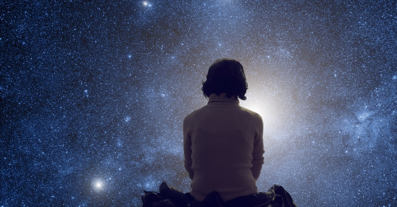 Woman sitting in front of a starry sky