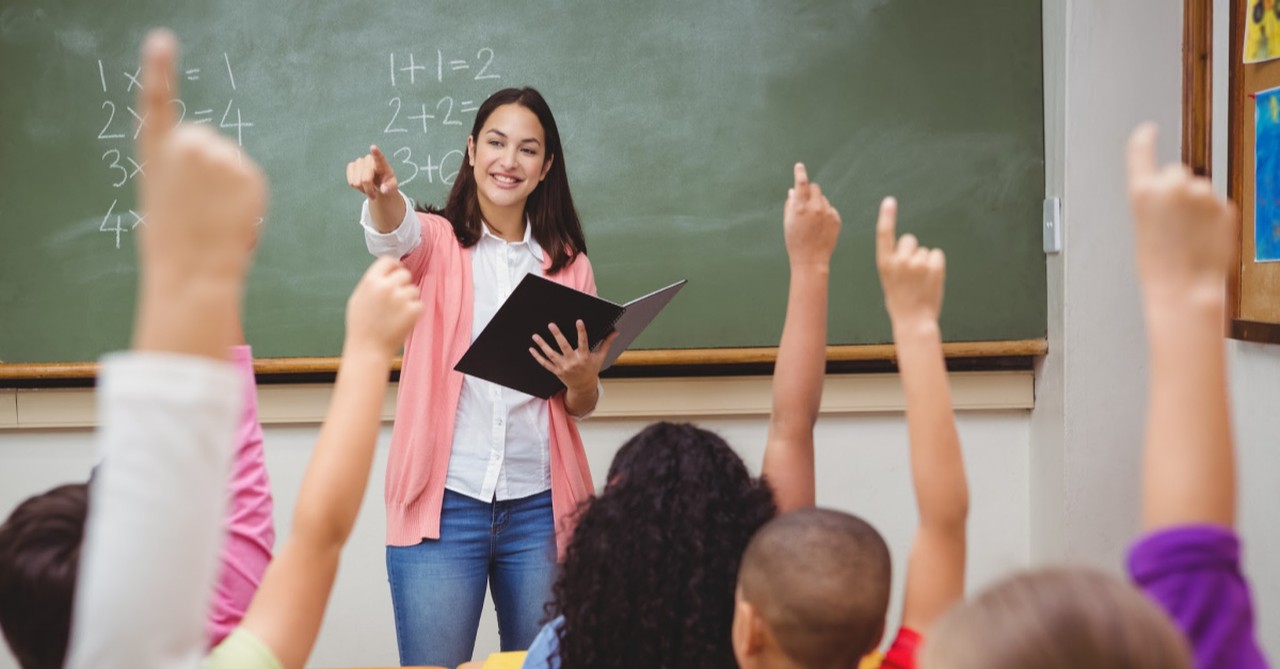 a teacher in front of a classroom, Our Lives Are Best Lived for Others