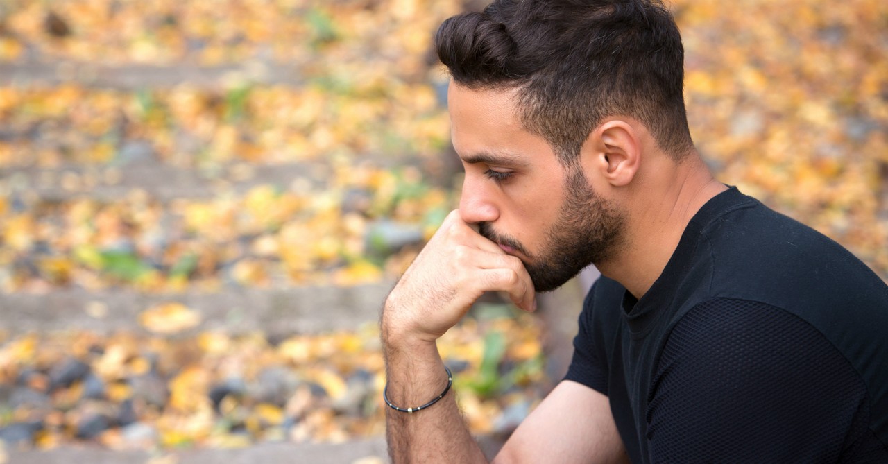 man pensive sad wondering outdoors, ways that normalization of anxiety can help and ways that it can hurt