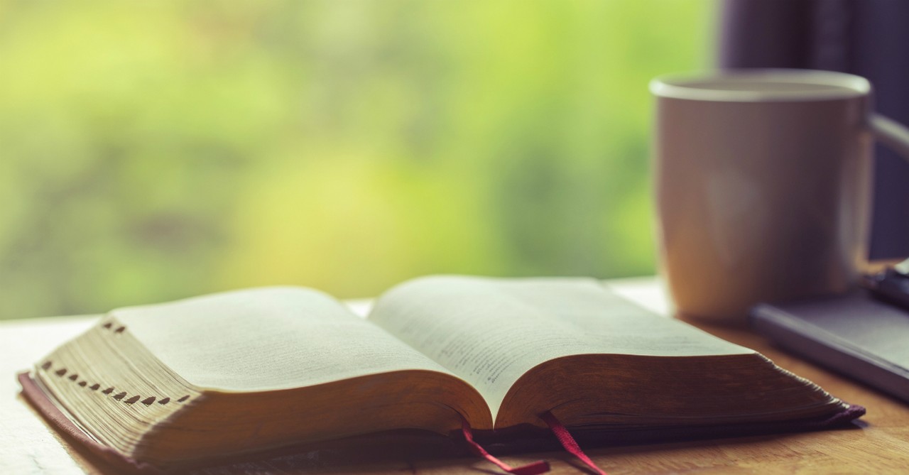 open bible next to coffee on table outdoors