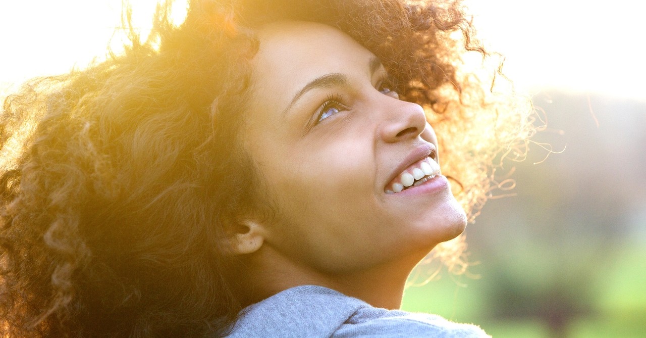 close up of woman looking up joyfully smiling, satisfied in god