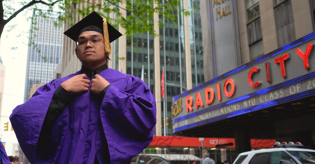 young man in college graduation gown and cap NYU city