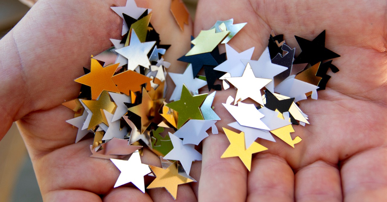 graduation caps and stars confetti in hands