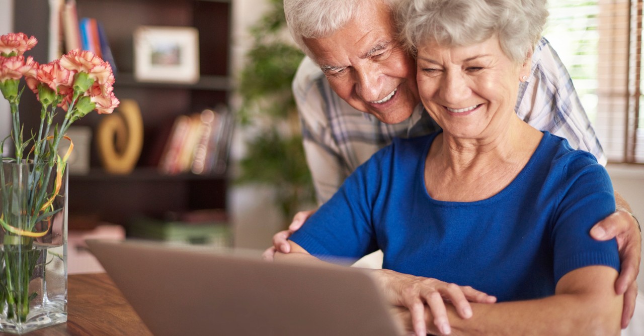 elderly couple smiling into laptop computer virtual technology