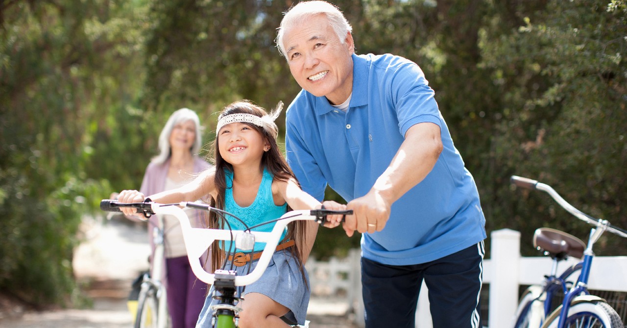 Senior man teaching a young girl how to ride a bike