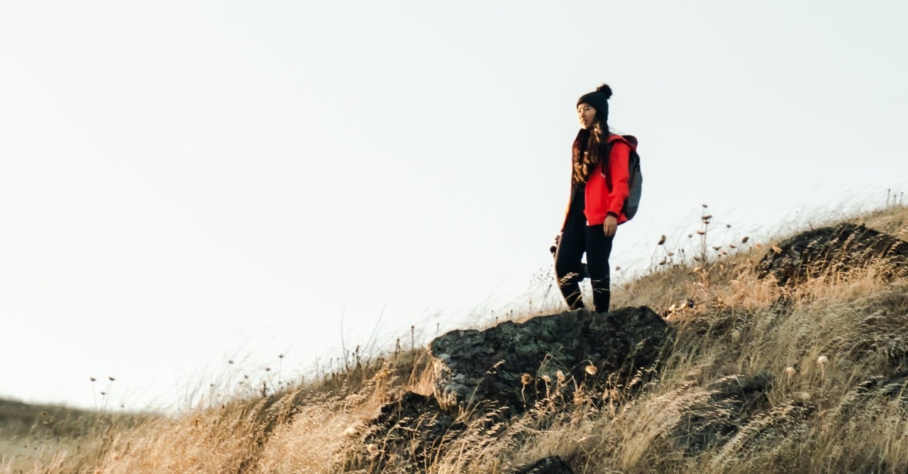 woman hiker standing on golden hill of grass looking forward, when you're afraid of falling behind