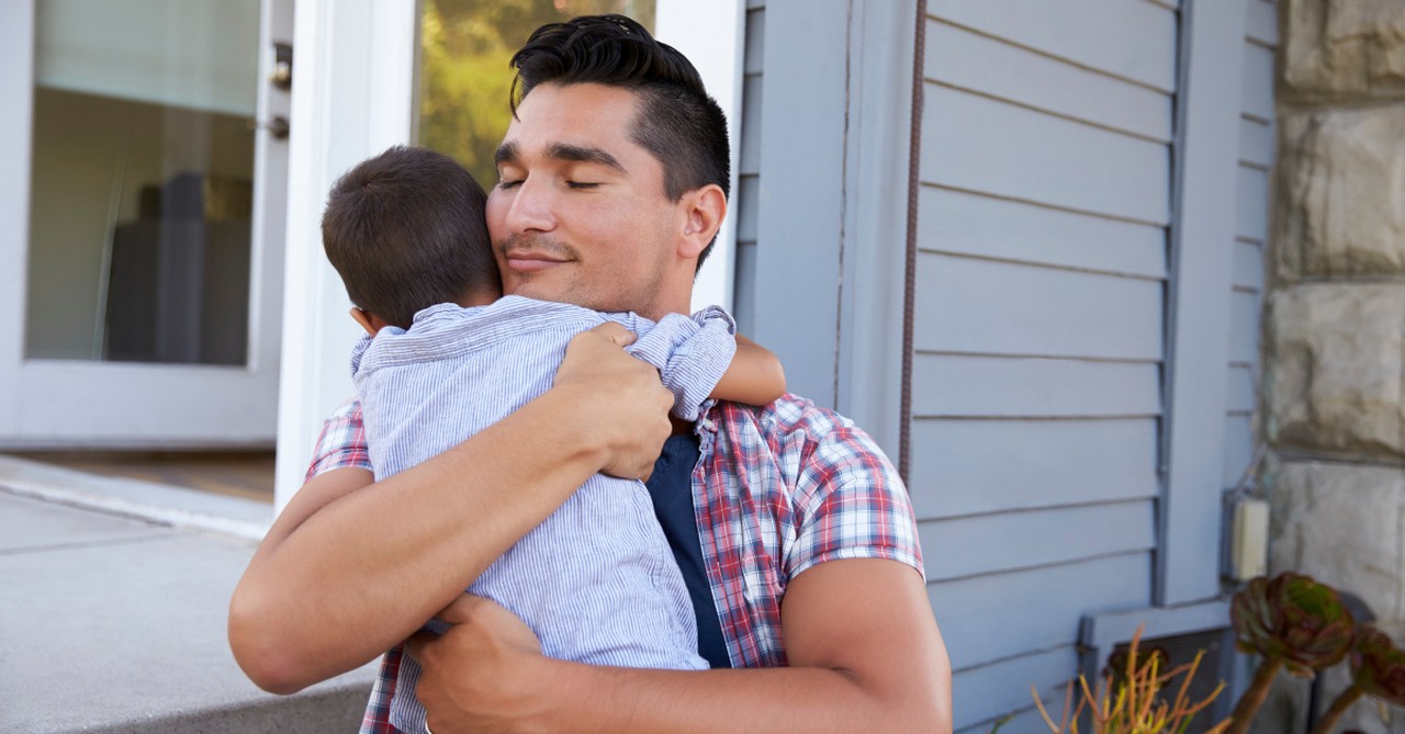 dad hugging toddler son joyful