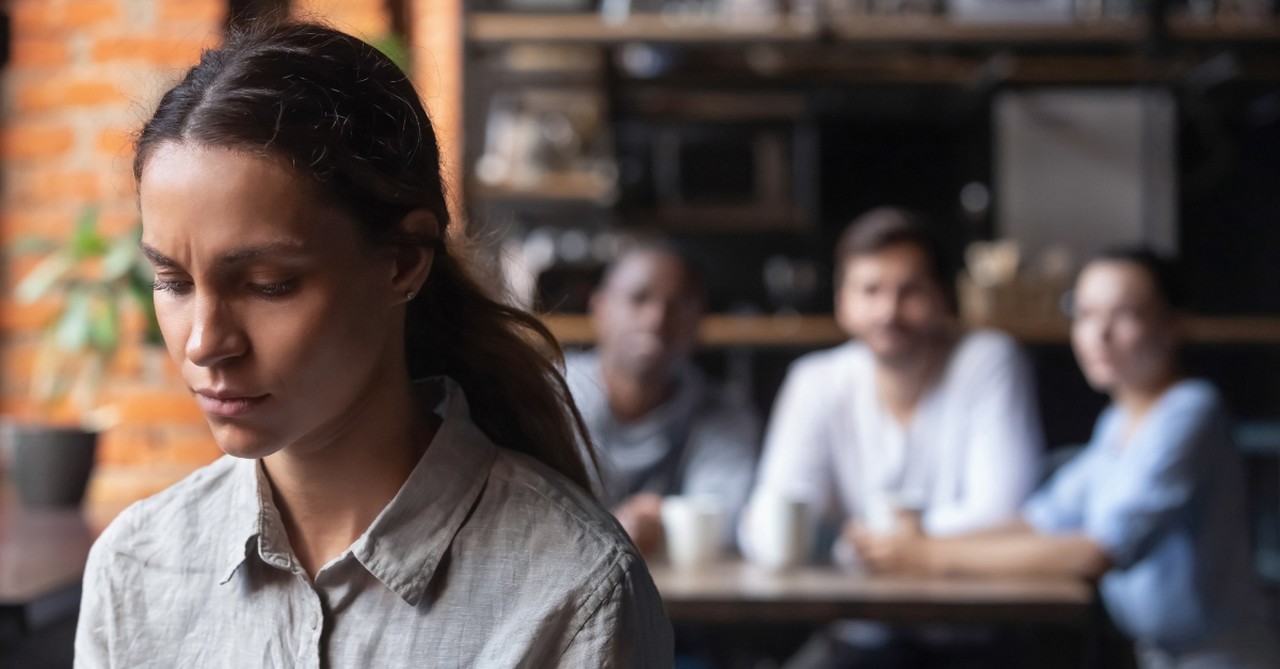 Sad woman listening to group talking about her