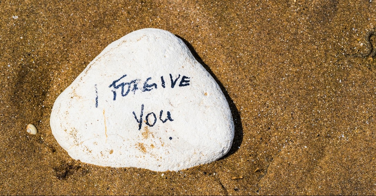 Rock on the beach that says I forgive you