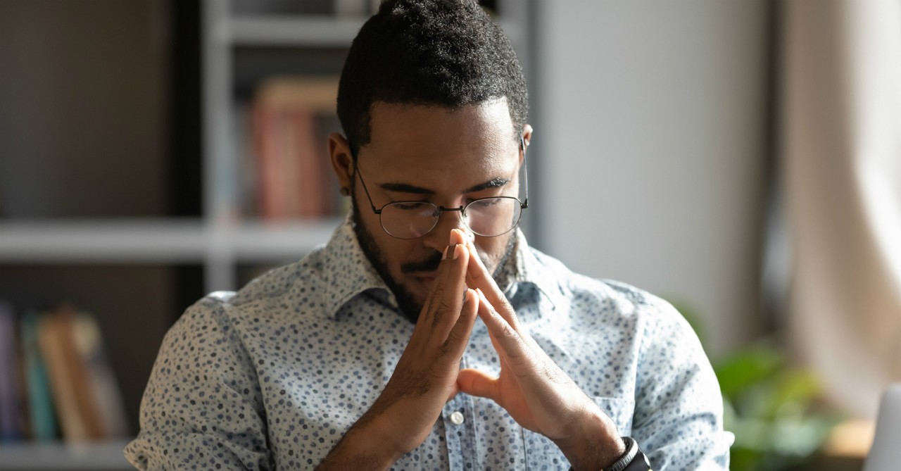 man with glasses praying at desk