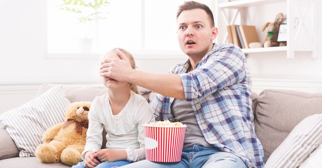 dad covering his daughter's eyes watching a movie