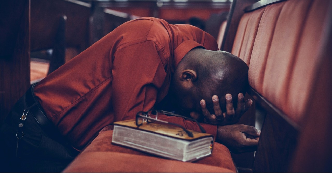 Man leaning on a pew with a Bible