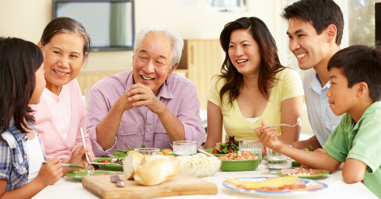 two generations family at dinner table granddad smiling at granddaughter