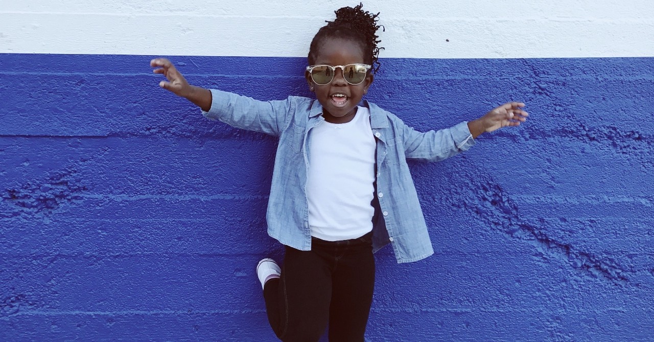 little smiling girl laughing standing in front of painted wall