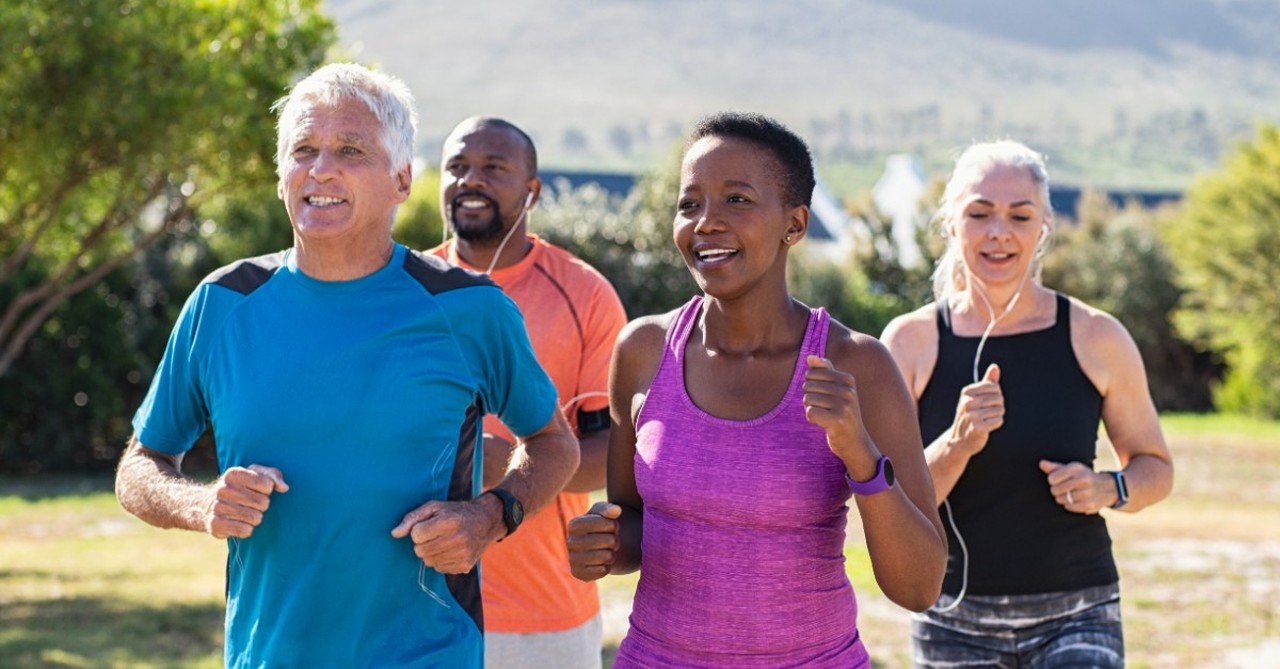 A diverse group of adults jog in a park together