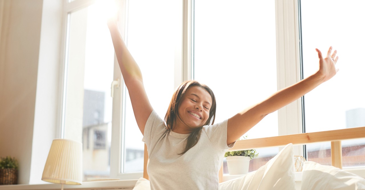 woman waking up in minimalist home joyful, wonderful time to be alive