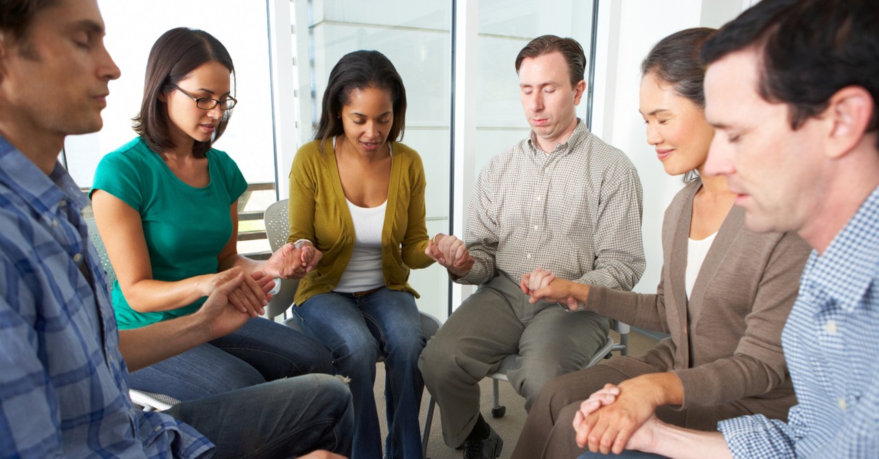 diverse group of adults in prayer circle together unity