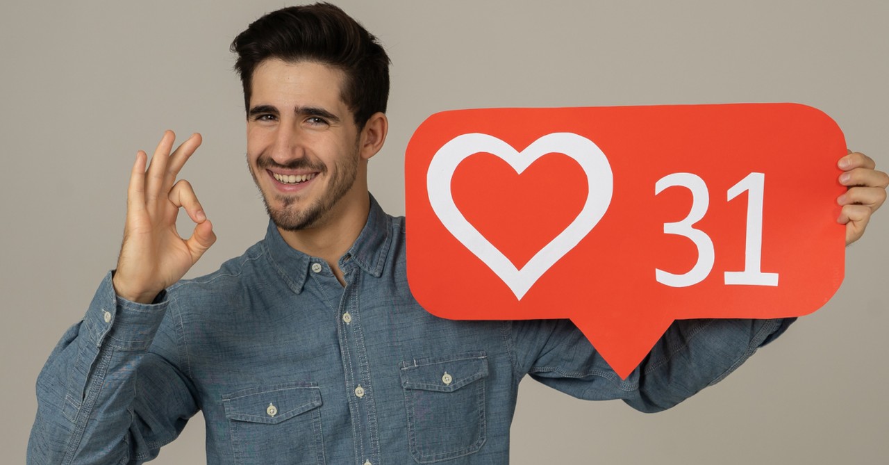 man proud of his social media likes holding heart emoji with 31 in it