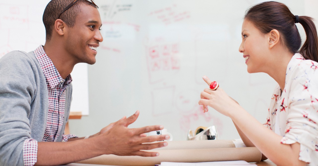 black man and asian woman at work smiling facing each other not color blind