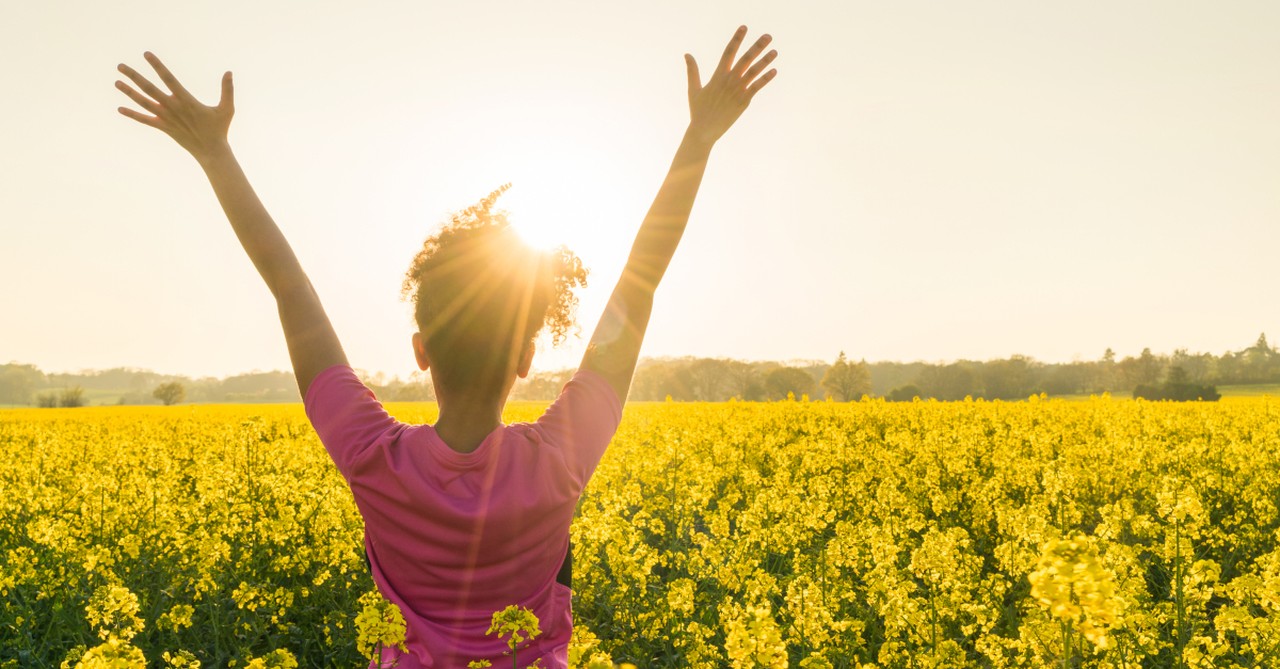 woman arms up in praise celebration gratitude in wildflower field