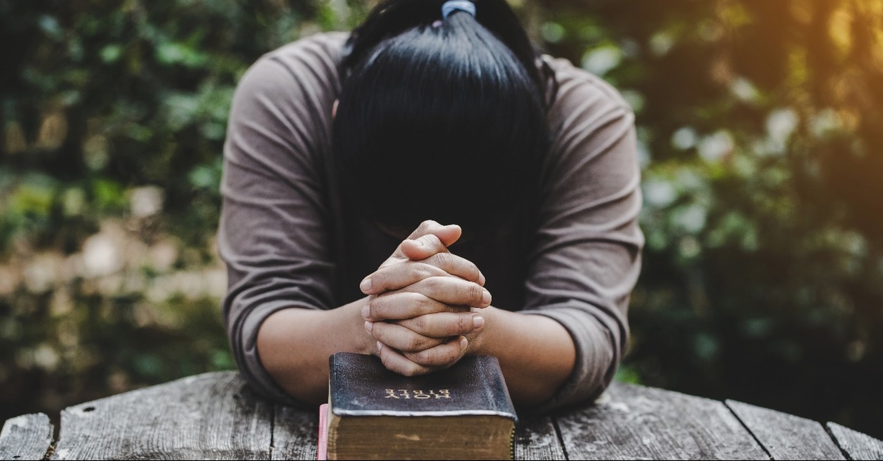 Woman praying over a Bible