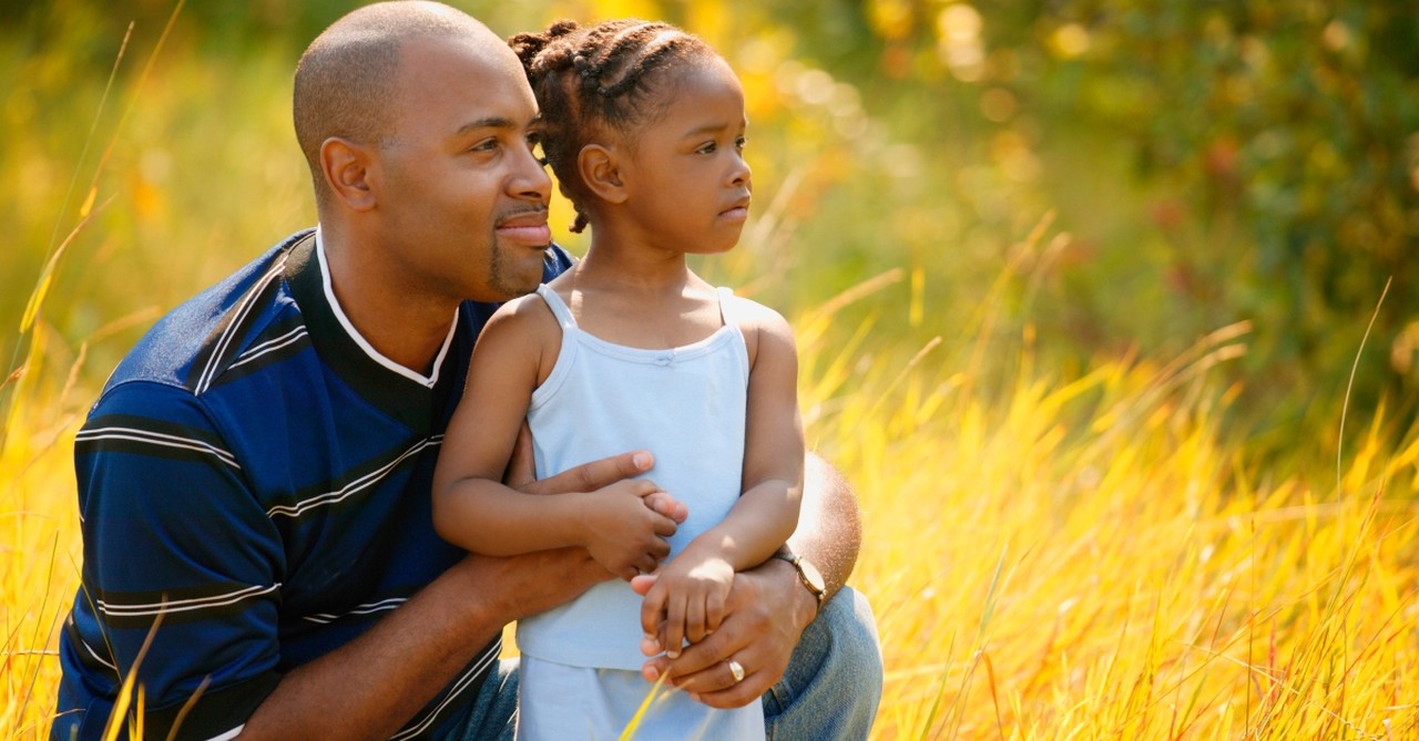 Dad and daughter in yellow field looking forward