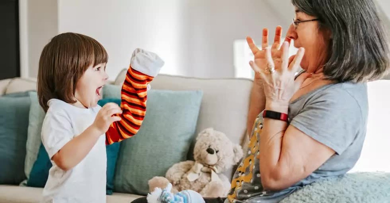 granddaughter playing puppets with grandmother