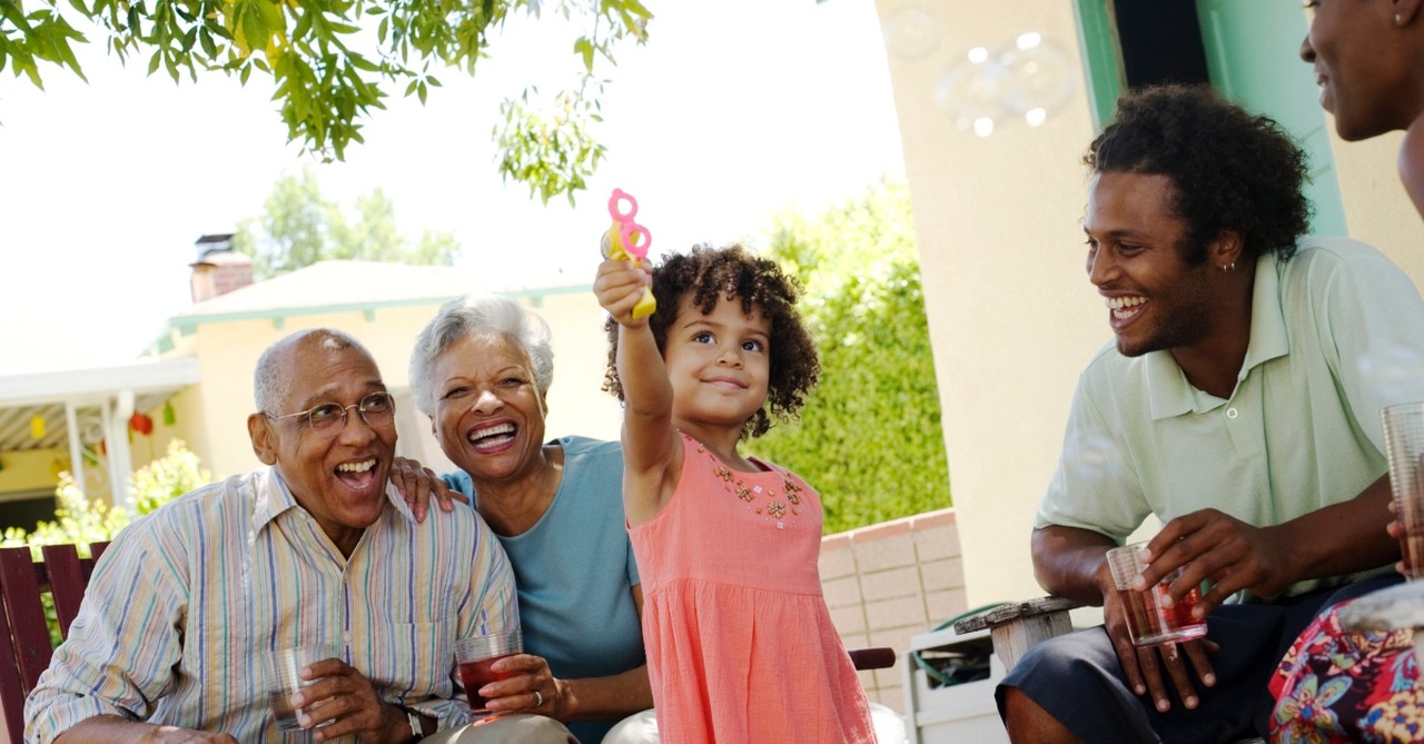 grandparents parents and granddaughter blowing bubbles smiling