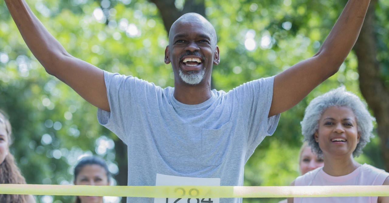 senior athletic man crossing race finish line joyful celebration