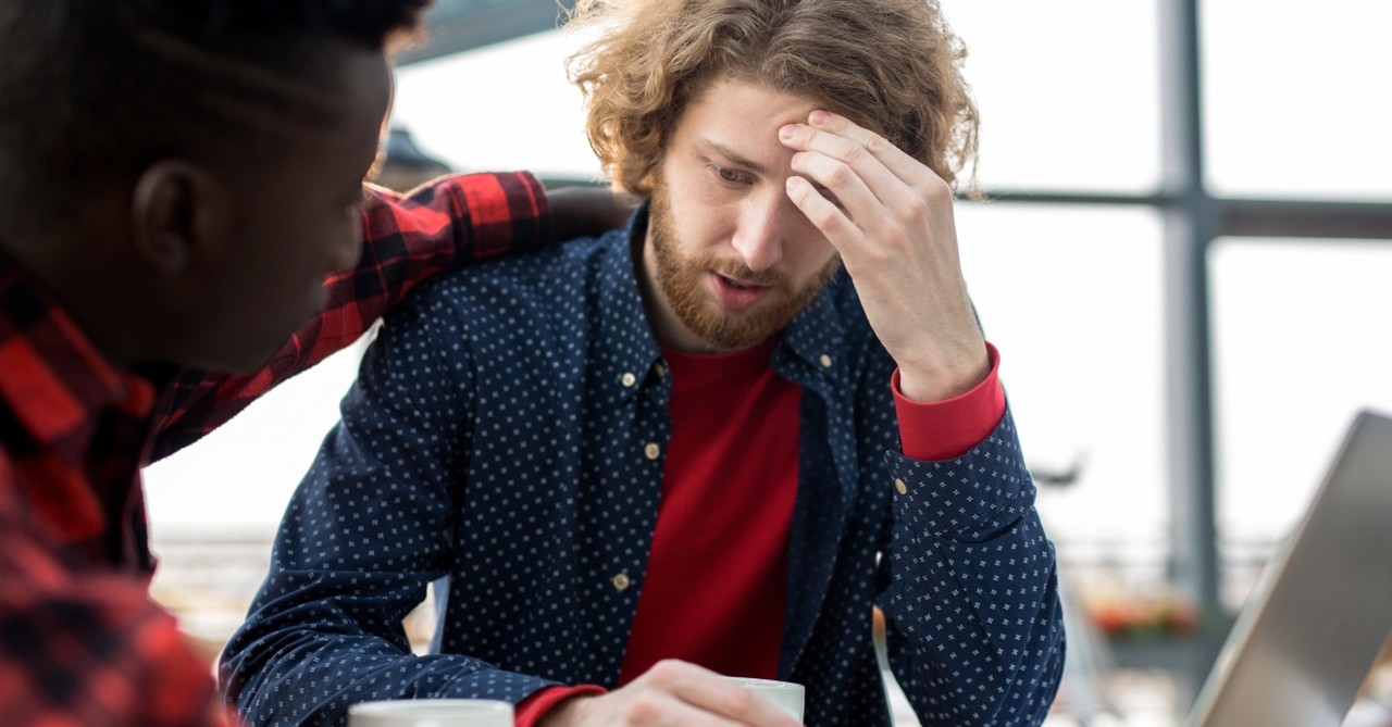 two men friends showing kindness having coffee with laptop